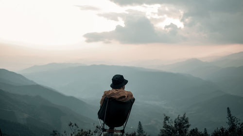 A man is sitting  on the peak and looking at the sky 