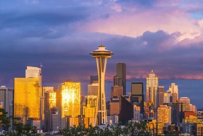 Modern buildings in city against sky during sunset