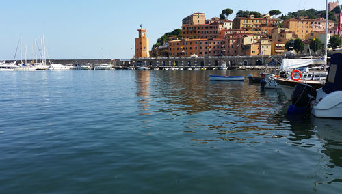 Sailboats moored in harbor against buildings in city