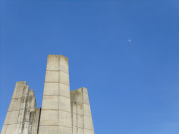 Low angle view of factory against clear blue sky