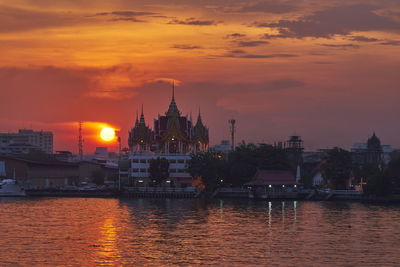 View of buildings at waterfront during sunset