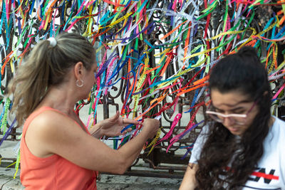 Portrait of two women placing colored ribbons on the church grid. 