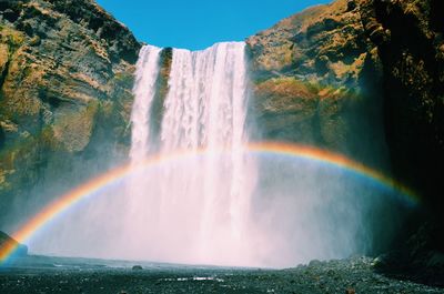 Scenic view of rainbow by waterfall