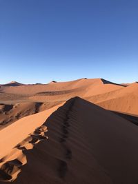 Scenic view of desert against clear blue sky