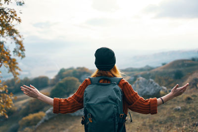 Rear view of man standing on mountain against sky