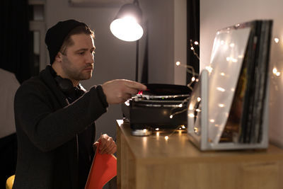 Young man sitting in illuminated room