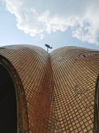 Low angle view of airplane flying over building against sky