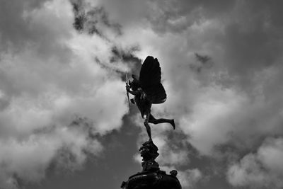 Low angle view of bird perching on tree against cloudy sky