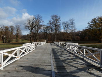 Footbridge amidst trees against sky