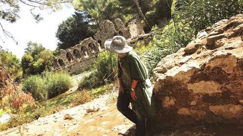 Rear view of woman standing on rock against trees