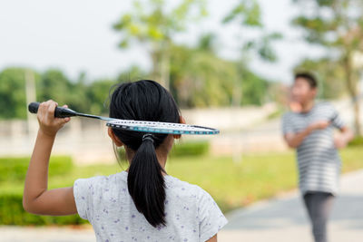 Rear view of girl playing badminton with friend