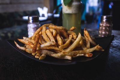 Close-up of burger with meat and fries in plate on table