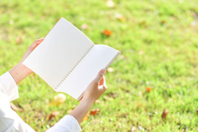 Midsection of person holding paper on field