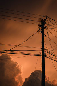 Low angle view of electricity pylon against sky during sunset