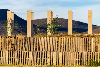 Fence by wooden post against sky