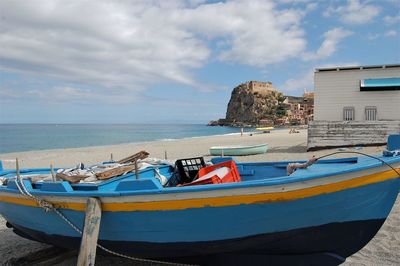 Boats moored on beach against sky