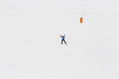 Man with umbrella on snowy field against sky