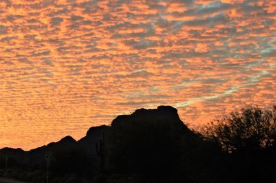 Low angle view of silhouette mountain against orange sky