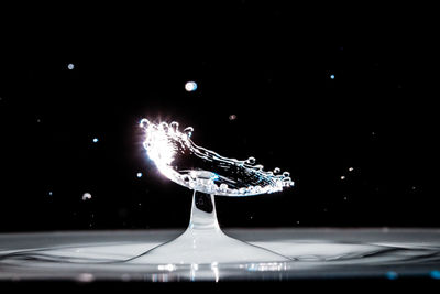 Close-up of illuminated water splashing against black background