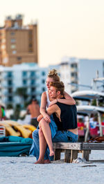 Full length of man sitting in city against sky