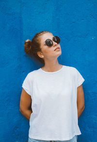 Woman looking away while standing against wall