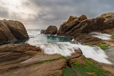 Scenic view of rocks on shore against sky