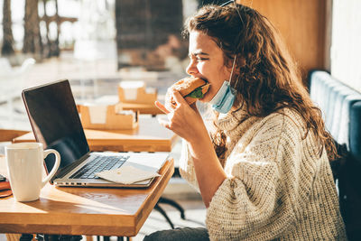 Young businesswoman using laptop while sitting on table