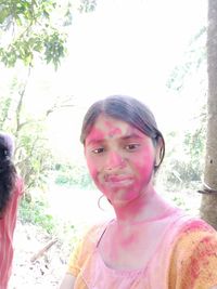 Portrait of smiling woman against pink and trees