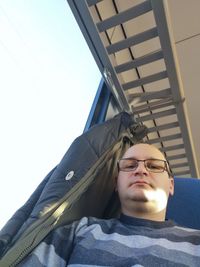 Low angle portrait of young man against sky