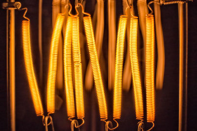 Close-up of illuminated lighting equipment hanging against wall