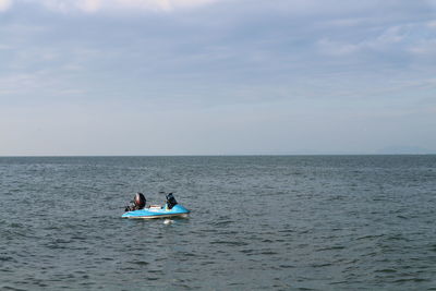 People in sea against sky