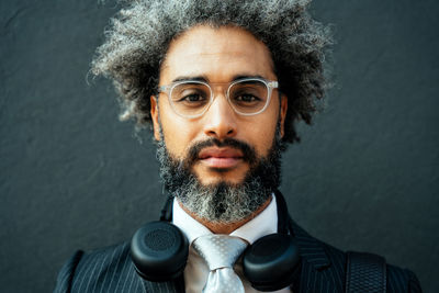 Close-up portrait of young man wearing eyeglasses against wall