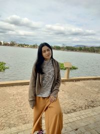 Portrait of beautiful young woman standing against lake