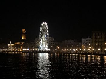 Illuminated buildings by river at night