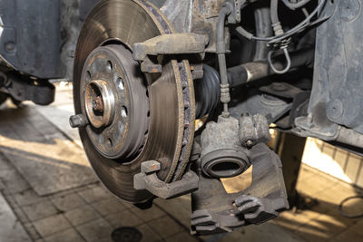 Disassembled front brake caliper on the car, which is on the car jack in the workshop.