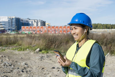 Smiling young man using mobile phone while standing on land