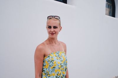 Portrait of smiling young woman standing against wall