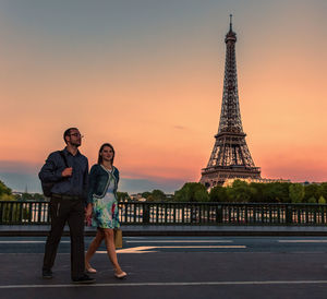Couple walking against eiffel tower during sunset