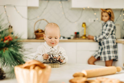 A little boy chooses cookie cutters on a table decorated with pine branches. sweet handmade 