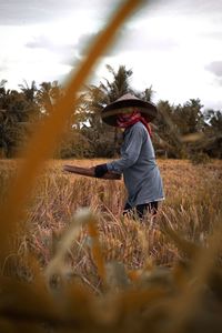 Woman wearing hat on field against sky