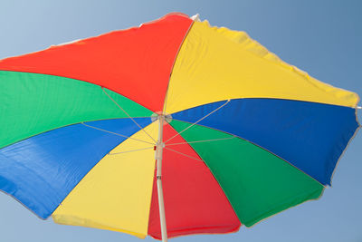 Low angle view of multi colored umbrella against blue sky