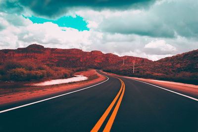 Road leading towards mountain against sky