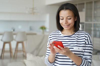 Happy woman holding smartphone, shopping on internet at home