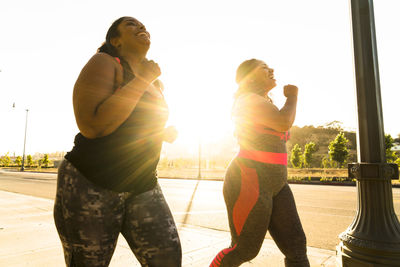 Low angle view of female friends jogging on footpath