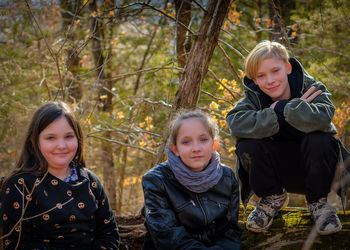 Portrait of smiling siblings standing in forest. 