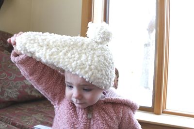Cute girl removing knit hat at home