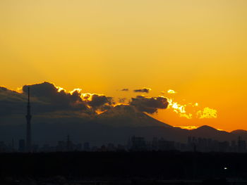 Smoke emitting from factory against orange sky