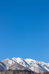 Scenic view of snowcapped mountains against clear blue sky