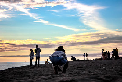 People on beach against sky during sunset