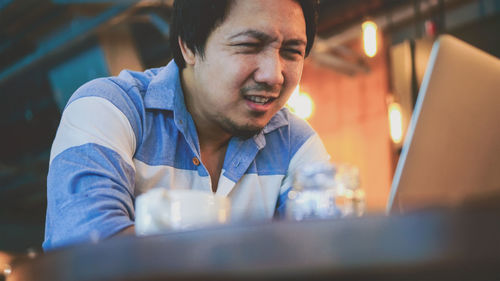 Low angle view of man using laptop in cafe